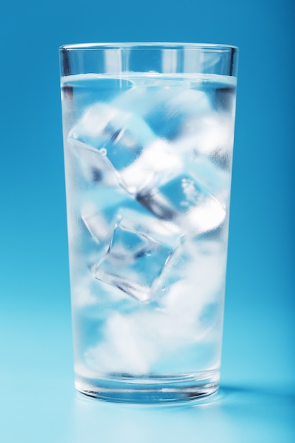 Un vaso con hielo y agua limpia en azul.