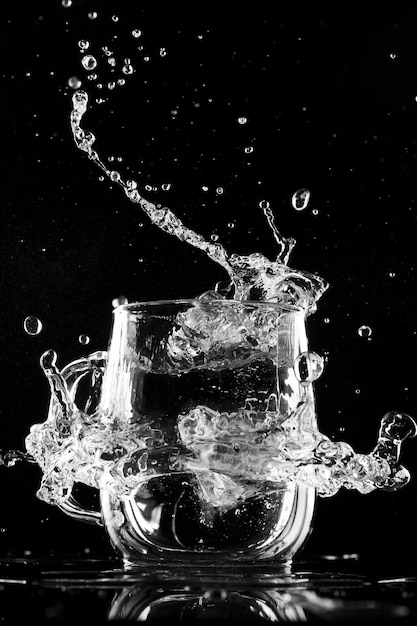 Foto vaso con hielo de agua y salpicaduras sobre un fondo negro