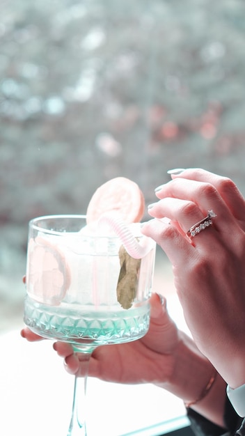 Foto un vaso con hielo y una mujer sosteniendo una cuña de limón