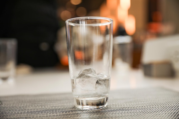 Un vaso de hielo se sienta en una mesa con una chimenea al fondo.