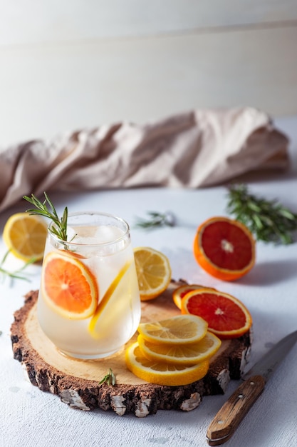 Un vaso y una jarra de limonada Rodajas de limón y pomelo con hojas de romero en una bebida