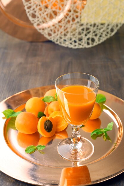 Vaso de jugo de albaricoque y frutas frescas en la mesa de cerca