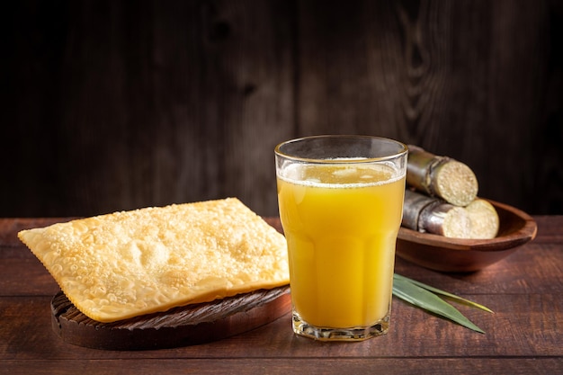 Vaso de jugo de caña de azúcar con pasteles fritos bocadillo típico brasileño