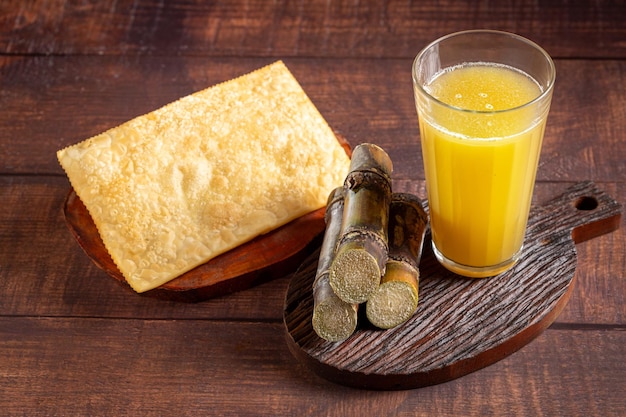 Vaso de jugo de caña de azúcar con pasteles fritos bocadillo típico brasileño