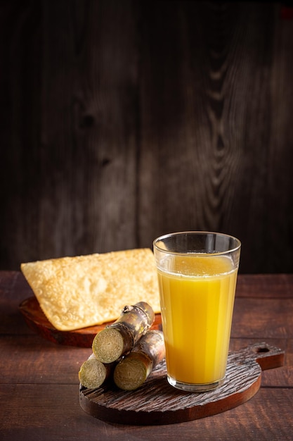 Vaso de jugo de caña de azúcar con pasteles fritos bocadillo típico brasileño