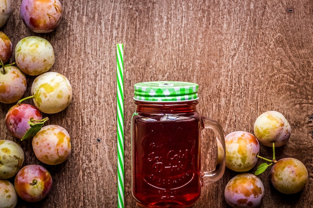 Vaso con jugo de ciruela fresca sobre fondo de madera vintage