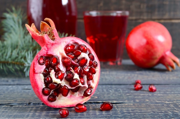 Un vaso de jugo de granada fresca con frutas de granada maduras en la mesa de madera. Vitaminas y minerales. Concepto de bebida saludable. De cerca