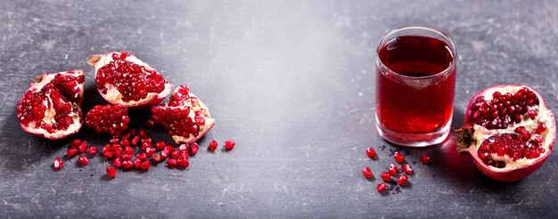 Vaso de jugo de granada con frutas frescas en la oscuridad