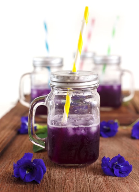 Vaso de jugo de guisante mariposa frío en la madera