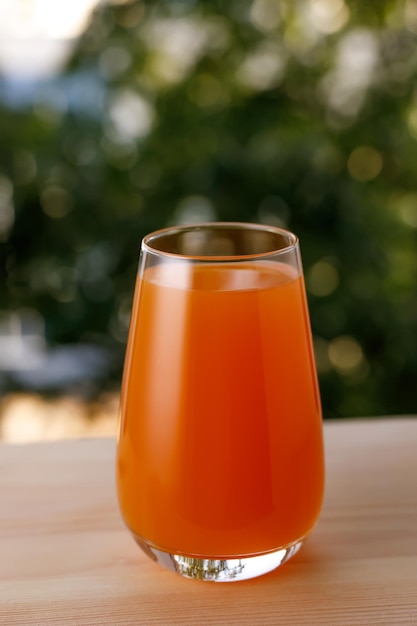 El vaso de jugo en un jardín La mesa de madera