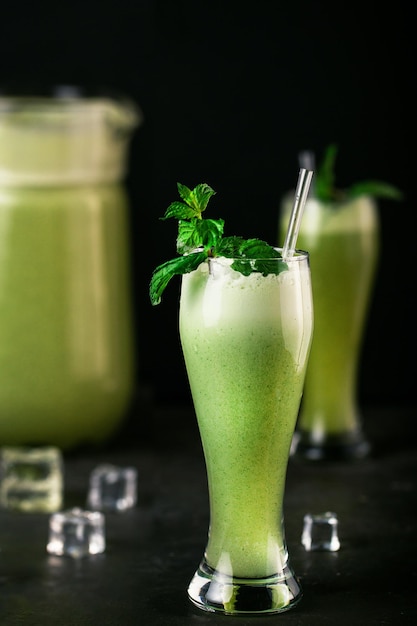 Vaso de jugo de limón con menta fresca sobre un fondo negro