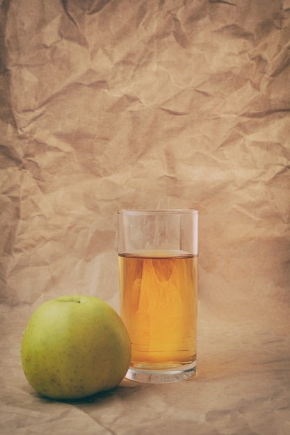 Un vaso de jugo de manzana con manzanas.