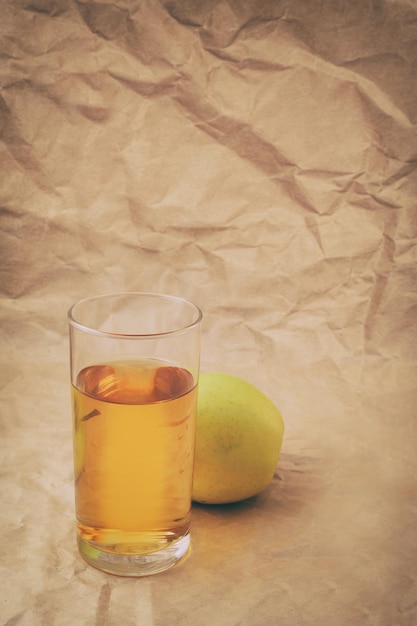 Un vaso de jugo de manzana con manzanas.