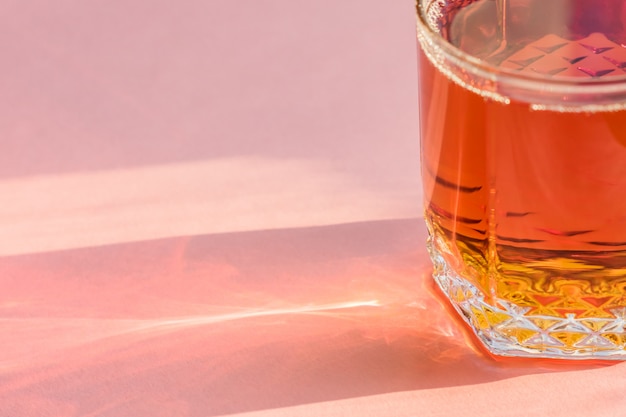 Vaso de jugo de manzana sobre fondo rosa