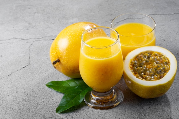 Vaso con jugo de maracuyá y maracuyá en rodajas sobre la mesa