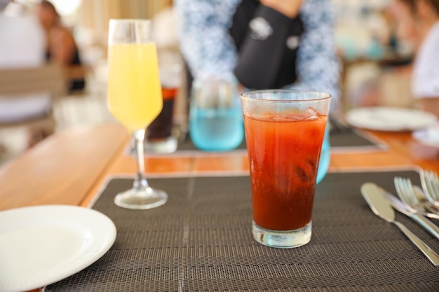 Un vaso de jugo de naranja y una bebida en una mesa.