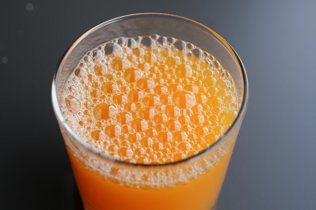 Vaso de jugo de naranja con burbuja en la mesa