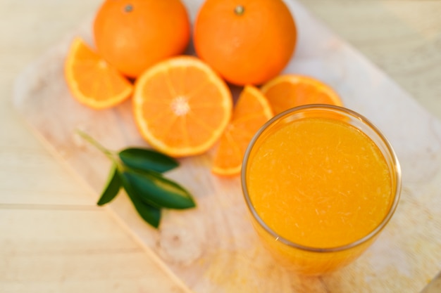 Vaso de jugo de naranja fresco con frutas frescas en la madera