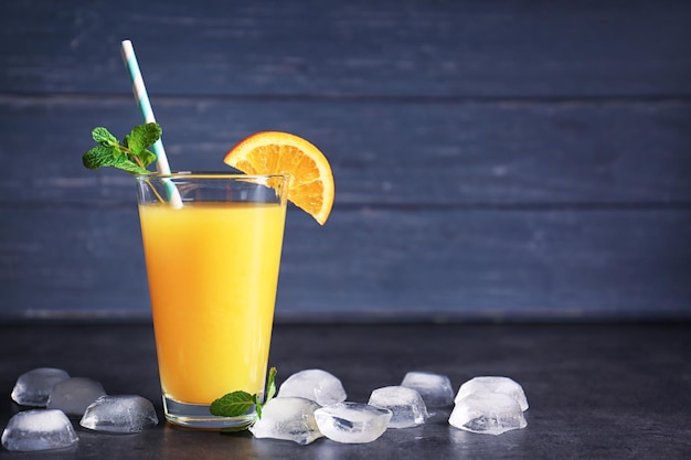 Vaso de jugo de naranja fresco con hielo en la mesa