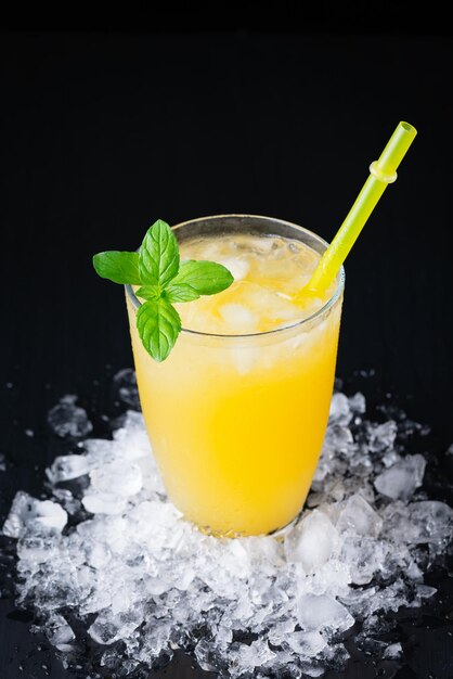 Vaso de jugo de naranja fresco con hielo sobre un fondo negro con un lugar para la inscripción