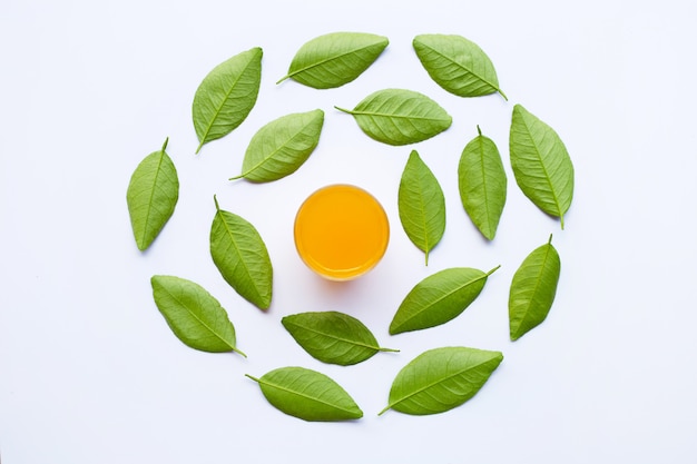 Vaso de jugo de naranja fresco con hojas verdes, aislado en blanco