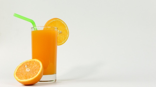 Vaso de jugo de naranja con fruta fresca cortada y pipa en fondo blanco