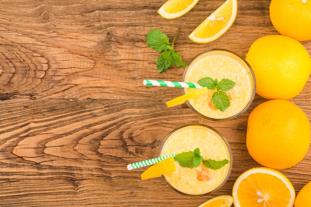 Vaso de jugo de naranja con frutas frescas en la mesa de madera