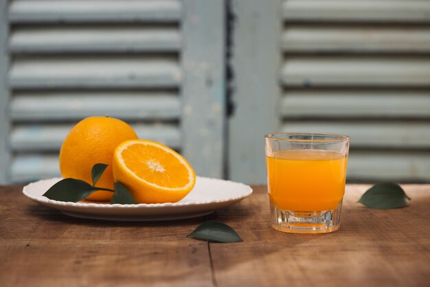 Vaso de jugo de naranja con frutas frescas sobre fondo de madera