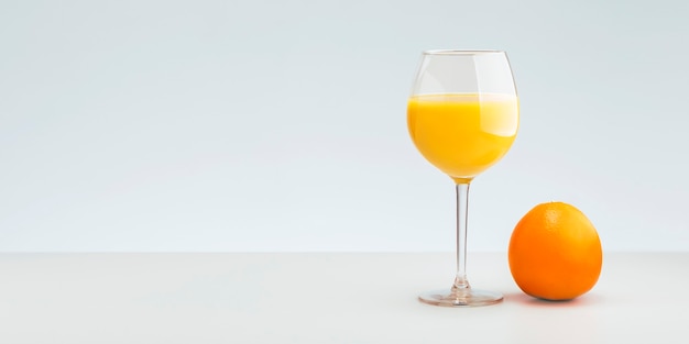 Vaso de jugo de naranja con frutas frescas