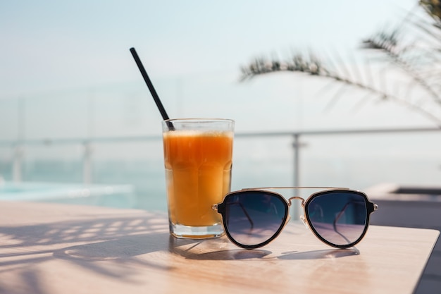 Un vaso de jugo de naranja y gafas de sol en el fondo del mar.