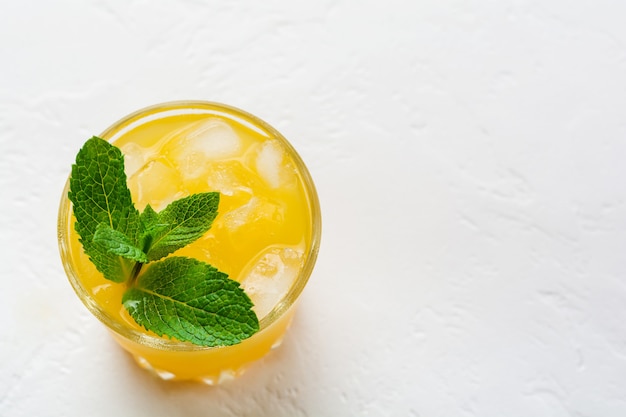 Un vaso de jugo de naranja con hojas de menta