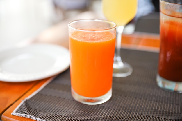 Un vaso de jugo de naranja junto a un plato de jugo de naranja.