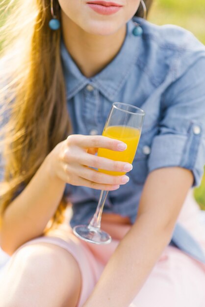 Vaso de jugo de naranja en la mano de una mujer joven