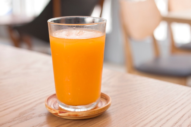 Un vaso de jugo de naranja en la mesa de madera