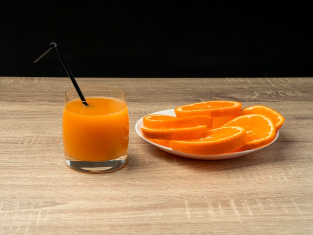 Vaso con jugo de naranja y naranja