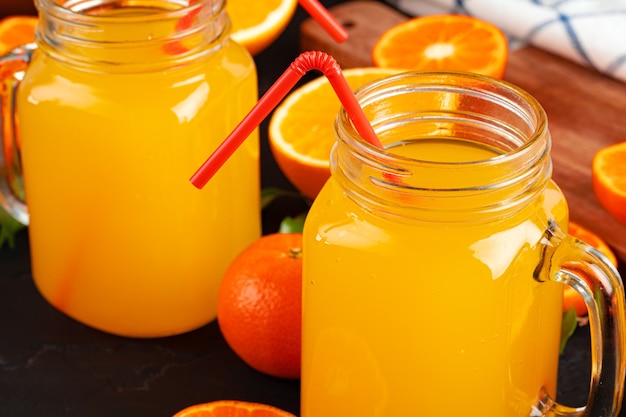 Vaso de jugo de naranja y naranjas cortadas en la mesa