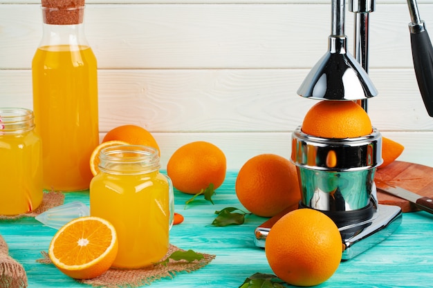 Vaso de jugo de naranja y naranjas cortadas en la mesa