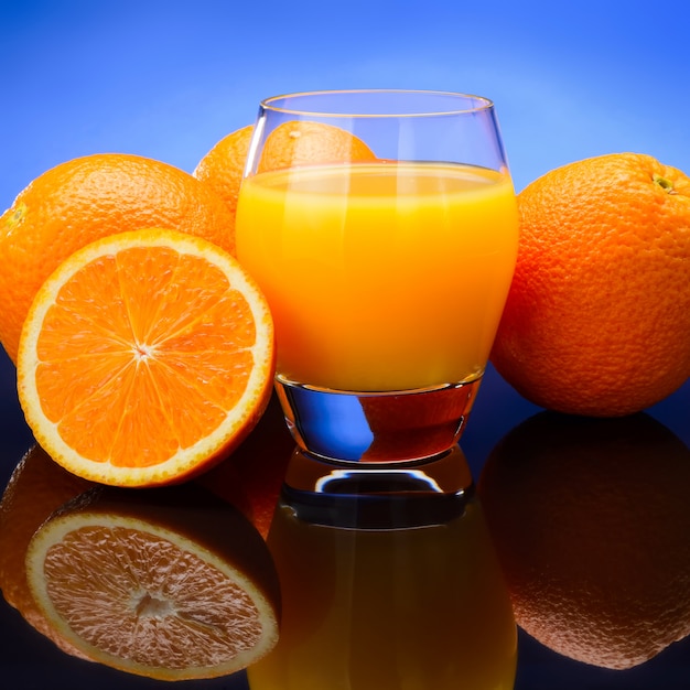 Vaso de jugo de naranja y naranjas