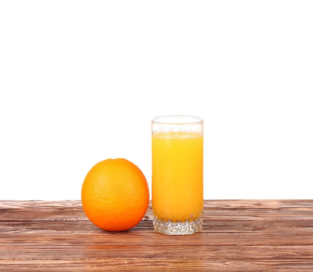 Vaso de jugo de naranja recién exprimido con rodajas de naranja mitad sobre mesa de madera