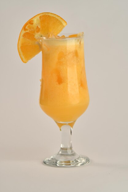 Un vaso de jugo de naranja con una rodaja de naranja.