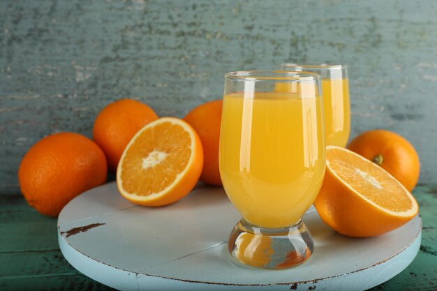 Vaso de jugo de naranja con rodajas sobre fondo de madera de color