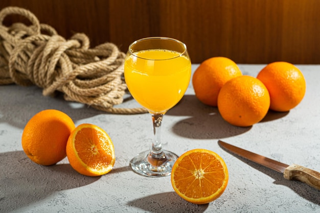 Foto un vaso de jugo de naranja se sienta en una mesa al lado de un racimo de naranjas.