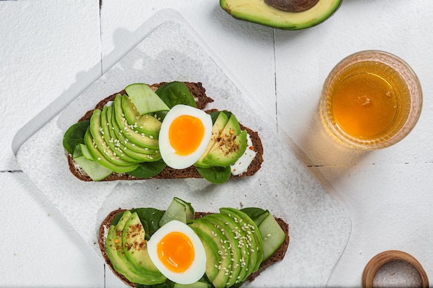 Un vaso de jugo de naranja se sienta en una mesa con tostadas de aguacate y tostadas de aguacate.