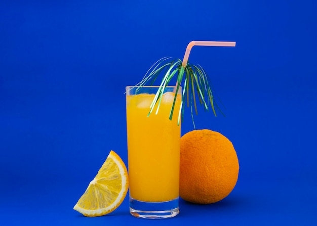 Un vaso de jugo de naranja sobre fondo azul.