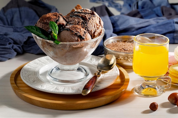 Un vaso de jugo de naranja y un tazón de helado con una cuchara al lado.