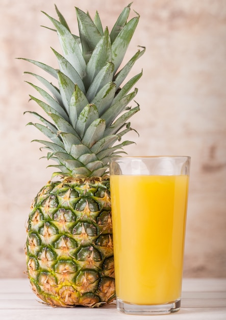 Vaso de jugo de piña fresca con fruta cruda sobre fondo de madera