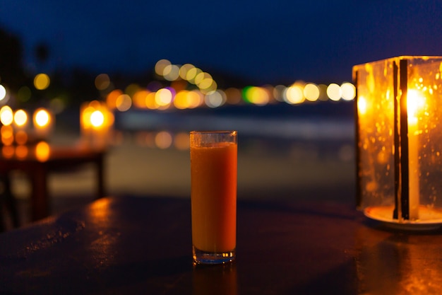 Un vaso de jugo recién exprimido en la noche en la playa