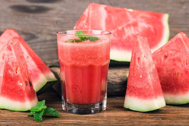 Un vaso de jugo de sandía fresca sobre un fondo de tablero de madera