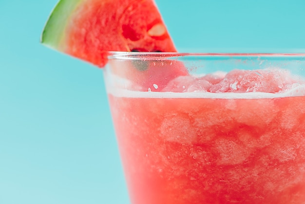 Vaso de jugo de sandía saludable en verano sobre fondo azul.