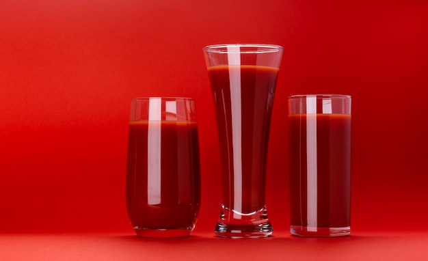 Vaso de jugo de tomate aislado en rojo